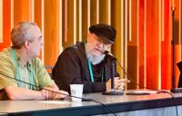 George R.R. Martin and Neil Clarke sitting at a table during panel discussion at Seattle Worldcon 2025
