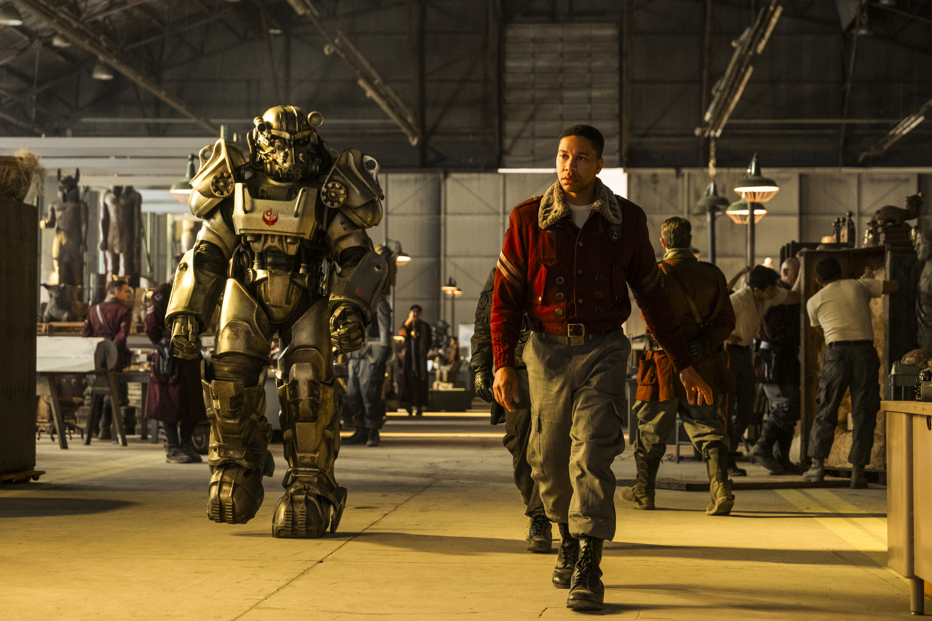 Aaron Moten walking next to someone in power armor