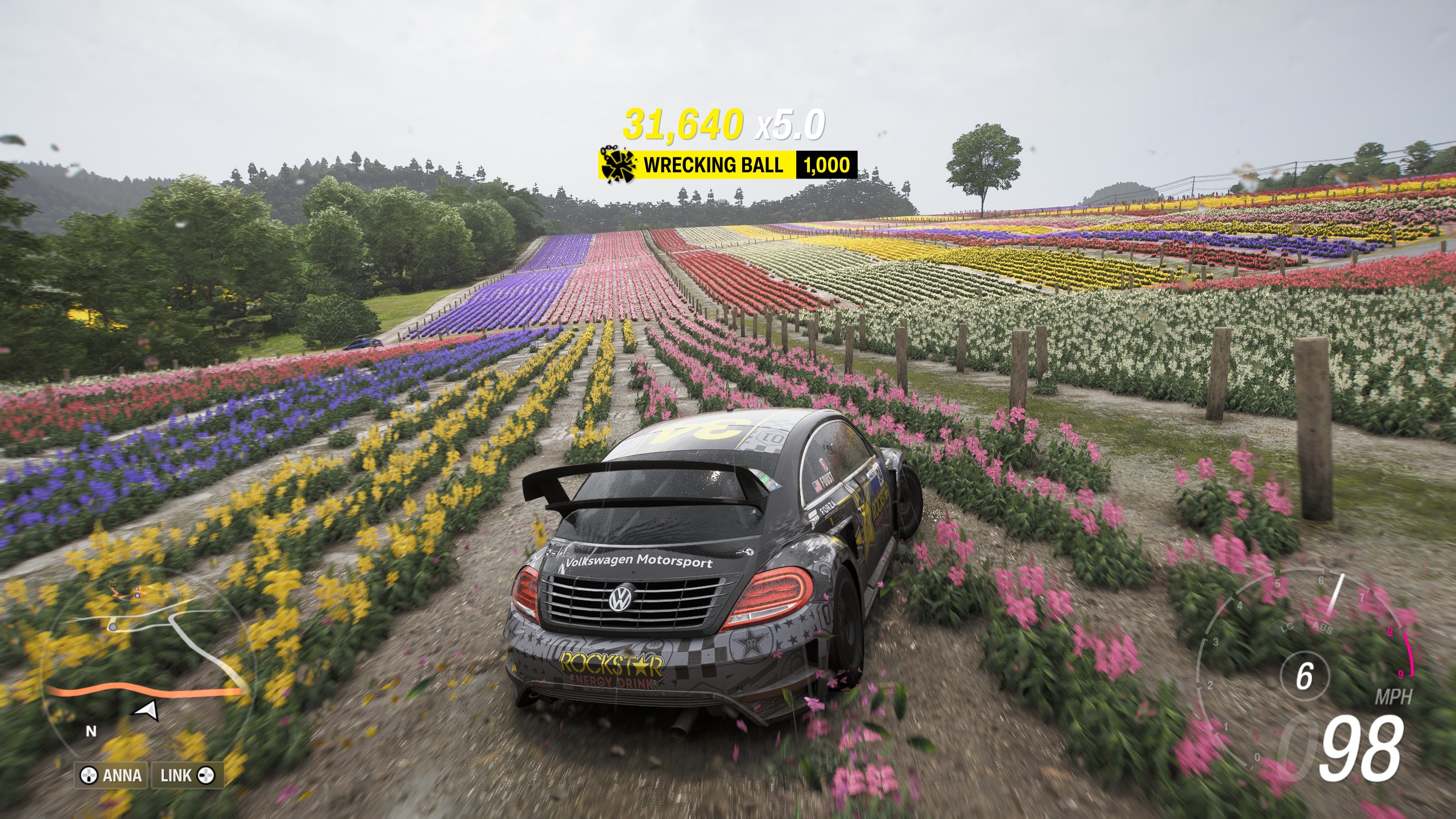 A car drifts through a field of multicoloured flowers.