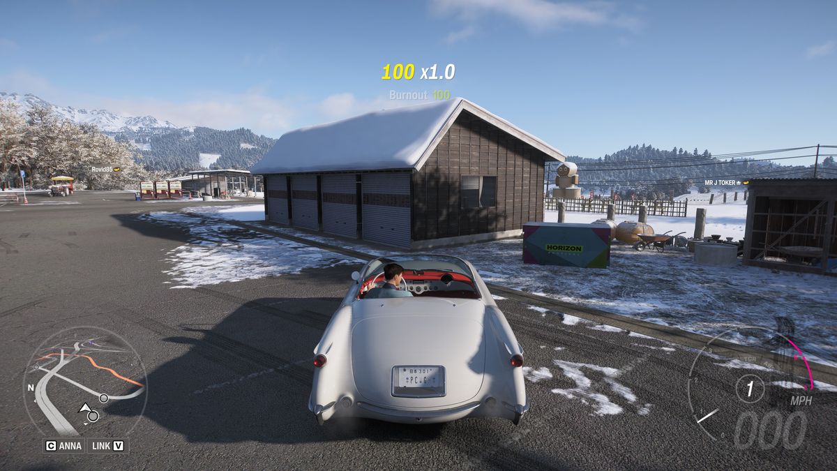 Forza Horizon 6 Hokubu Treasure Hunt: A white classic car parked next to a treasure chest outside a wooden building in a snowy field.