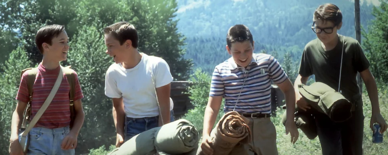 A still from 1986's Stand by Me, showing the four main boys walking down a train track.